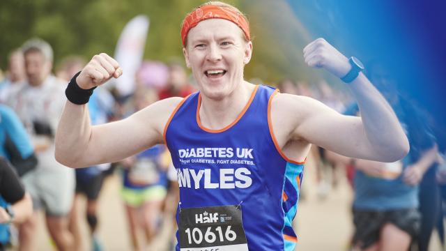 Male runner fists in the air in Diabetes UK running vest looking triumphant.