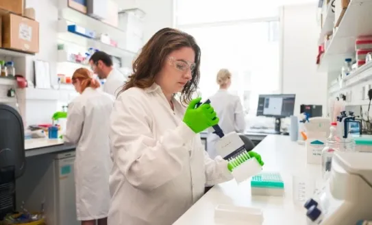 Researcher in lab with bright green gloves
