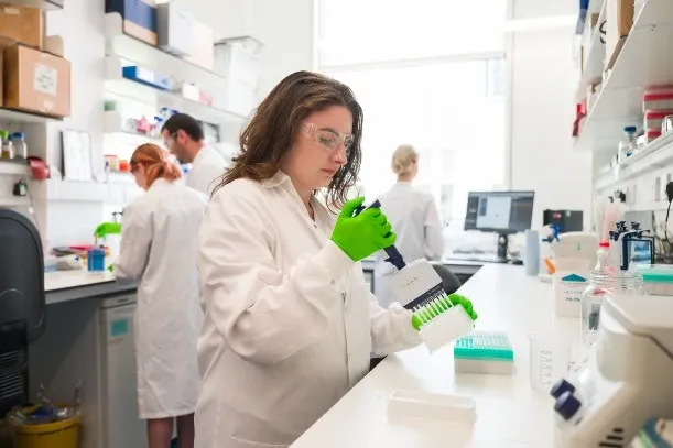 Researcher in lab with bright green gloves
