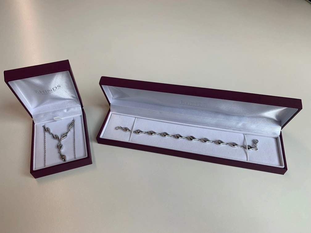 Two red boxes of F.Hinds jewellery. One contains a silver bracelet and the other contains a silver necklace.