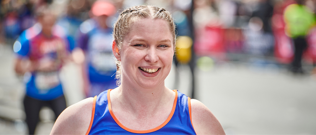 Woman running the Edinburgh Marathon wearing blue Diabetes UK running vest and smiling at camera.