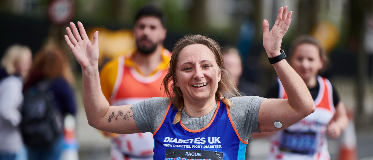 Female runner arms raised wearing a Diabetes UK vest.