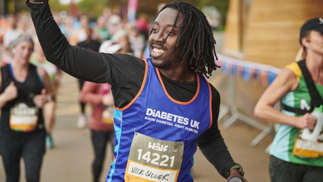 A male runner smiling and waving to the crowd.