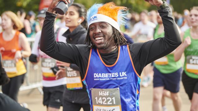 A male runner smiling and waving to the crowd.