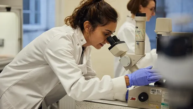 Woman diabetes researcher looking down a microscope at King's College