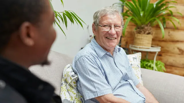 Smiling older man seated talking to a younger man, also seated