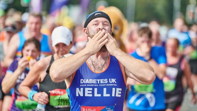 Participant in a Diabetes UK running vest taking part in a road race, surrounded by other runners.