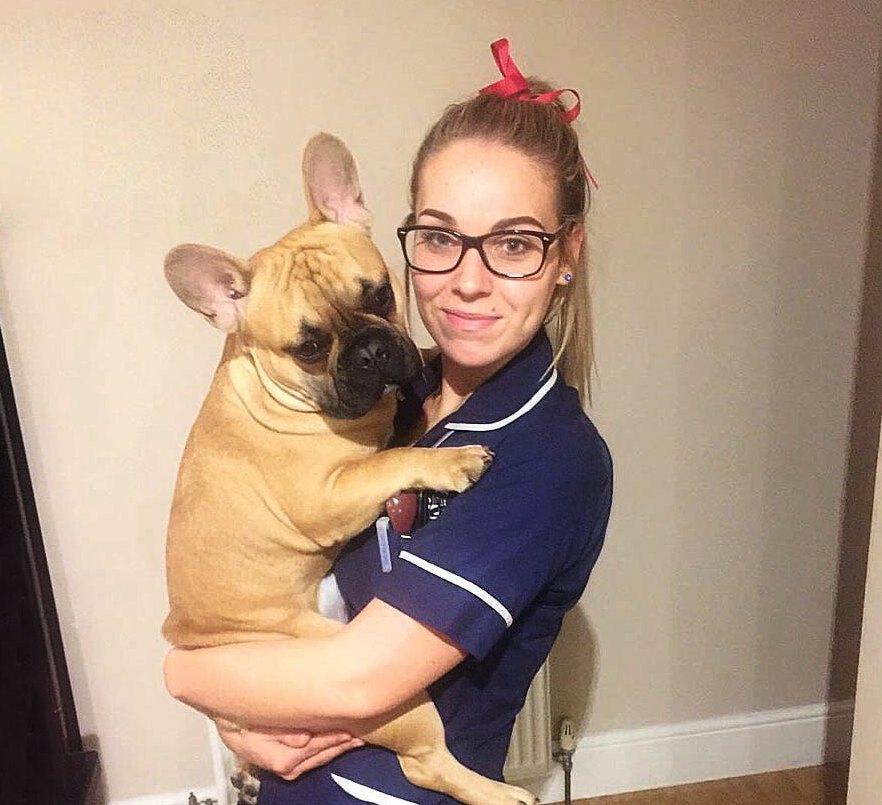 Hannah smiles to the camera, holding her dog