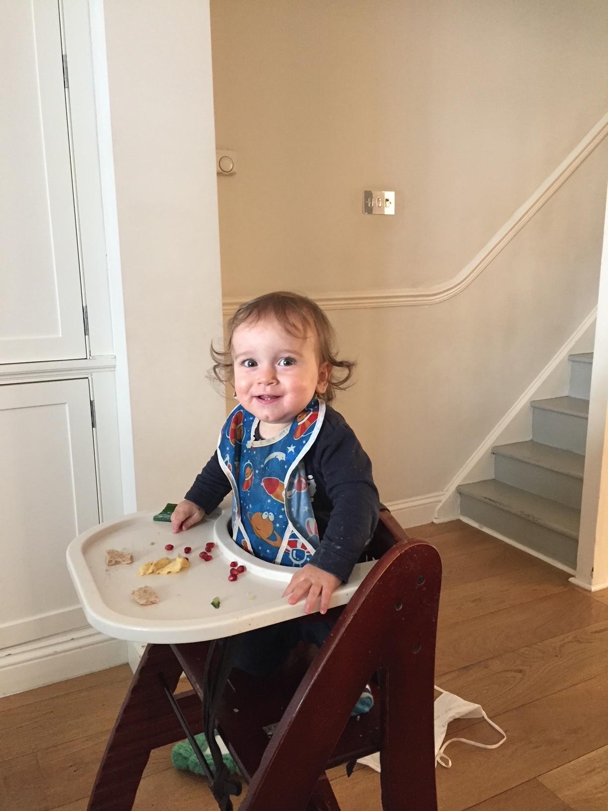 A young child in a high-chair eating food