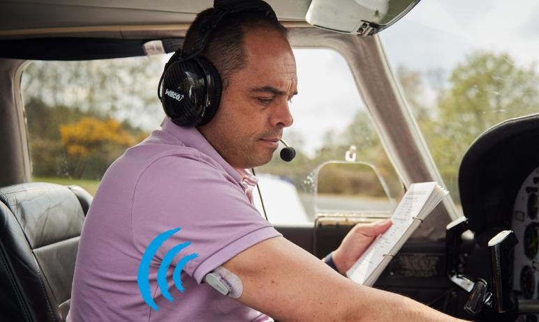 Chris sat in an aeroplane with his CGM sensor on his arm