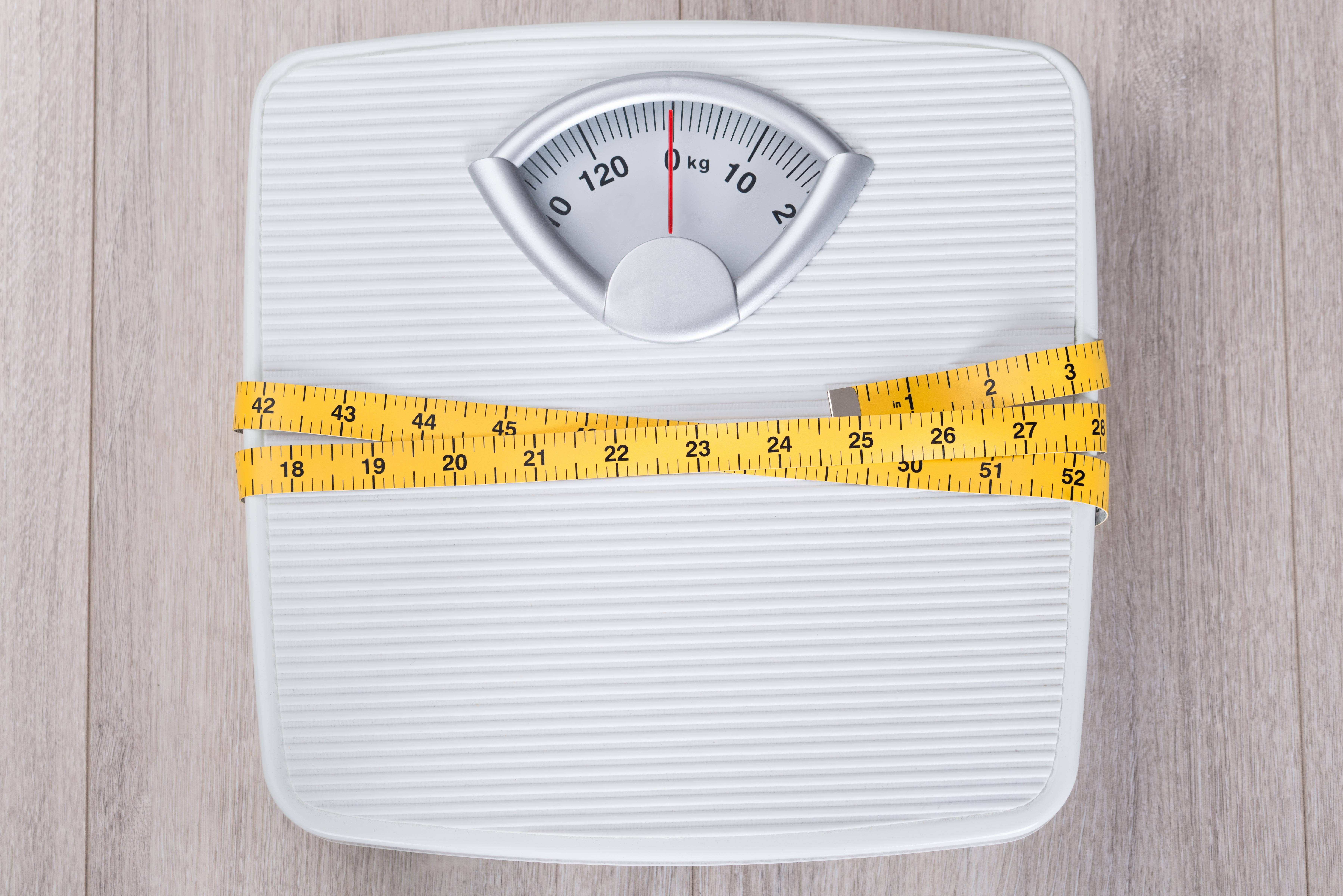White weighing scales with a measuring tape wrapped around them