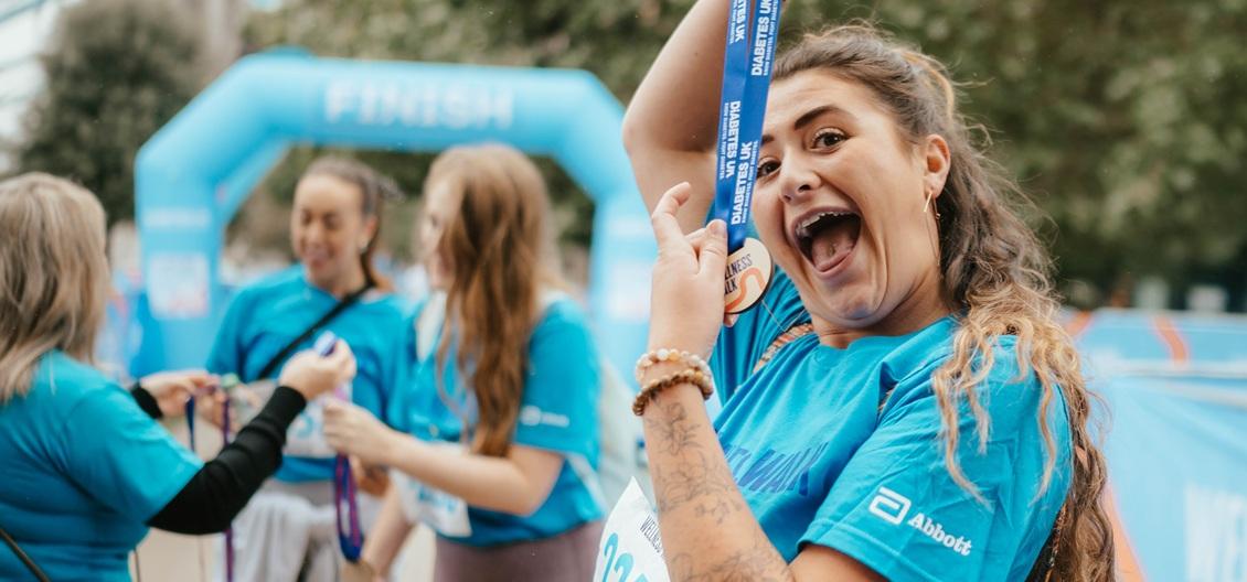 a woman celebrates with her wellness walks medal
