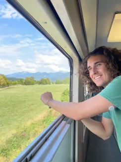 A young man looks out of a train window onto a field