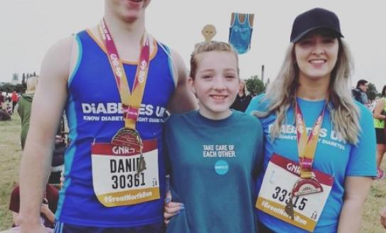 Pic shows Daniel and Leanne smiling at the end of the race with their little sister Erin standing in between them. The three of them have their arms round each other.