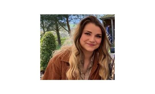 A photo of Lucy, a young Caucasian woman with long blonde hair, smiling to camera
