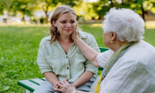 young woman old woman in park sad