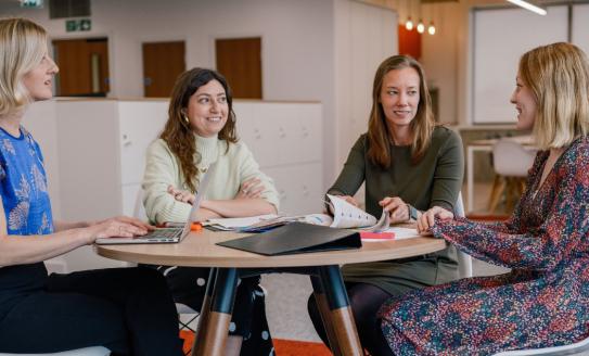 4 people gathered around a table having a meeting