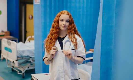 Thalia in a hospital next to a hospital bed in nurse uniform