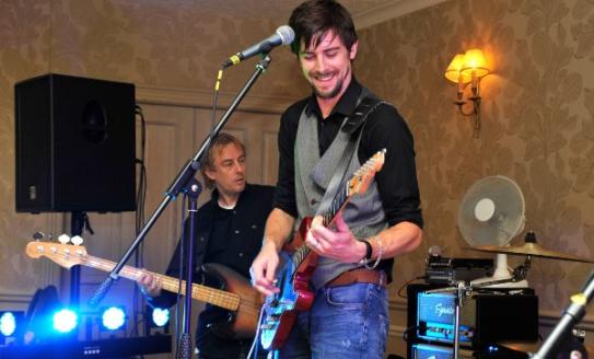 The image shows a young man playing guitar.
