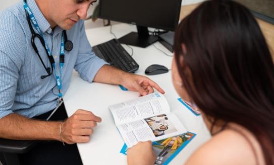 The image shows a Doctor with a patient reading through a leaflet.