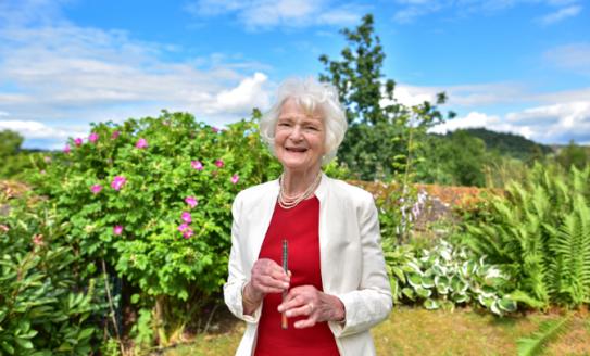 Dr Sheila Reith standing in her garden, holding her insulin pen prototype