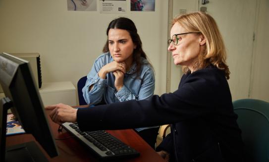 A GP sitting at a computer with a patient