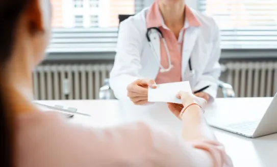 doctor hands prescription to patient