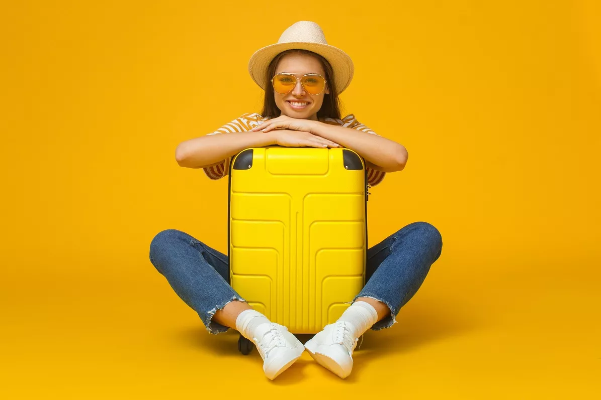 young traveller hugging yellow suitcase