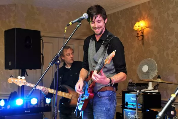 The image shows a young man playing guitar.