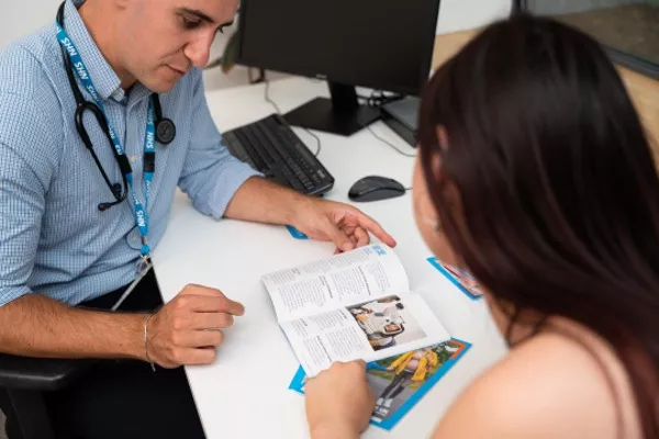 The image shows a Doctor with a patient reading through a leaflet.