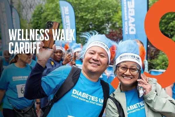 The image shows two people wearing blue t-shirts. There is text that reads 'Wellness Walk Cardiff'.