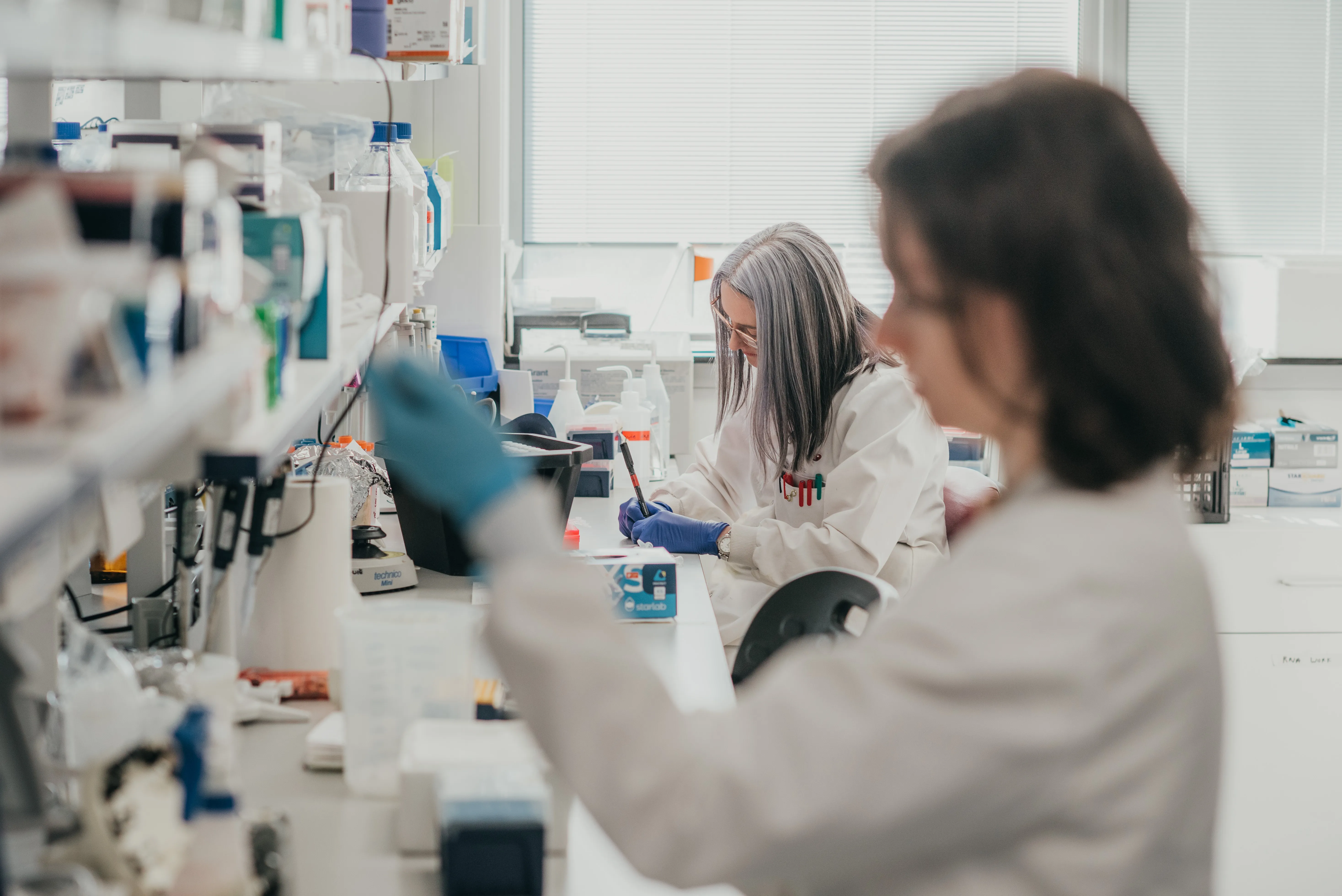 Photo showing two scientists in lab pipetting