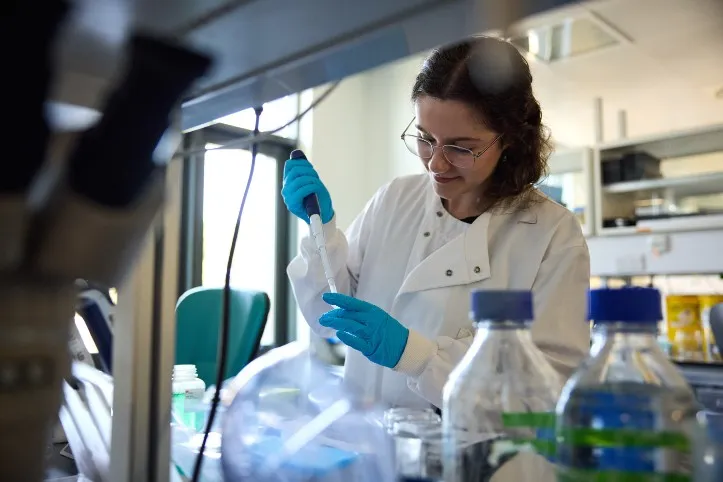 A photo of a research in the lab with blue gloves on pipetting
