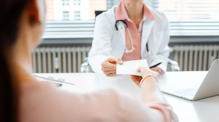 doctor hands prescription to patient