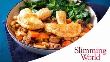 A white bowl with steak, mushrooms, carrots, and beans, puff pastry, and greens