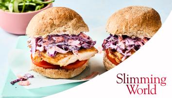 Two rolls with peri-peri chicken, tomato slices, and slaw on a blue rectangular plate