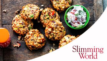 Chunky bean burgers on a wooden cutting board with a small green bowl filled with yoghurt, tomatoes, and spring onions