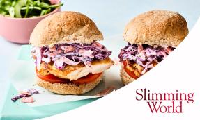 Two rolls with peri-peri chicken, tomato slices, and slaw on a blue rectangular plate