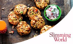 Chunky bean burgers on a wooden cutting board with a small green bowl filled with yoghurt, tomatoes, and spring onions