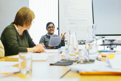 Two people sitting round a table discussing and reading papers.