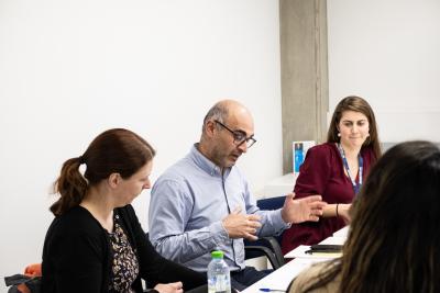 Three healthcare professionals sit at a table chatting in an office