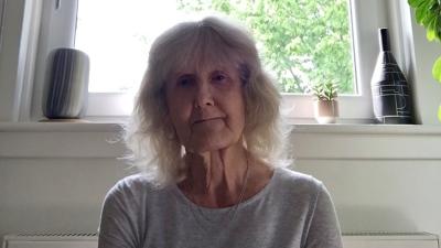 A woman wearing a white top is sitting by a window